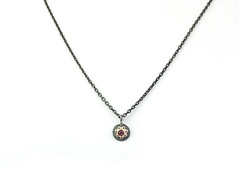 Matte oxidized silver pendant with a 750mm rose gold center and natural Ruby with a dark silver chain. Matte oxidized silver pendant with a 750mm rose gold center and natural Ruby with a dark silver chain.