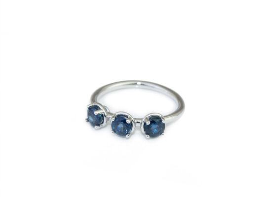 Anell or blanc de 750mm amb 3 safirs blaus naturals. Grapes sobre base.
