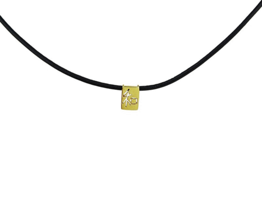 Collar de piel con colgante de oro amarillo con símbolo de caligrafía Kanji. “WA”